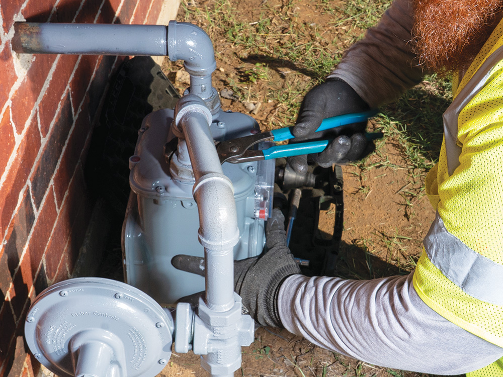 A gas Service Operations Technician replaces an old meter with a new meter at a residence.