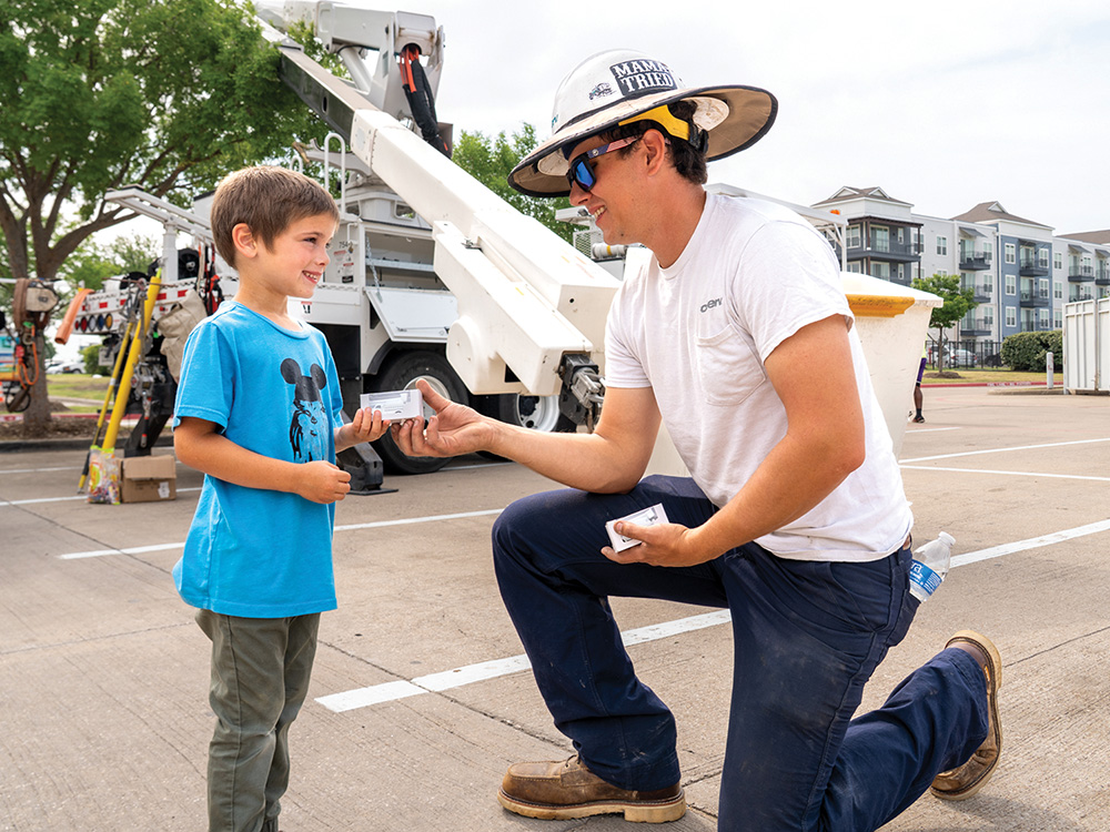 C: CoServ Lineman Kenny Beutter passes out a model of a CoServ bucket truck at the Little Elm Town Expo &amp; Touch A Truck Event.