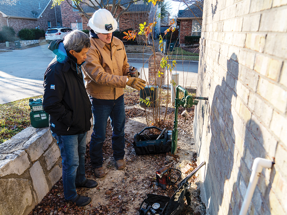 CoServ Gas Operations Field Supervisor Alex Copeland talking to a homeowner while checking the pressure on a residential meter for a new move-in.